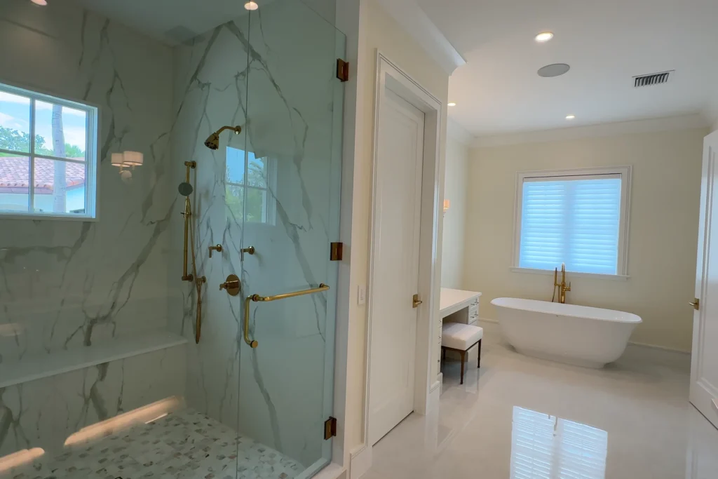 Frameless glass shower enclosure with clear tempered glass and satin brass hardware at a White Pelican Way residence in Jupiter, FL by ACG Glass & Metals