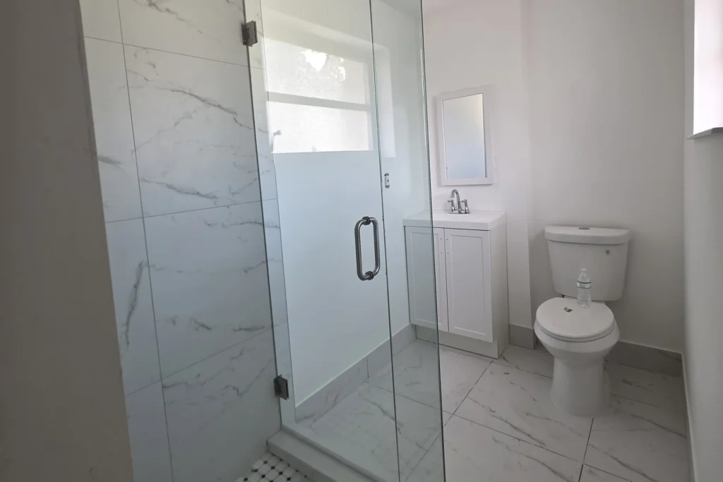 Frameless clear glass shower enclosure with brushed nickel hardware in a Wilma Circle residence, West Palm Beach, FL